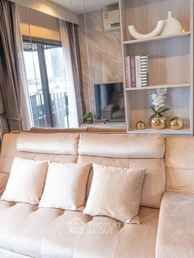 Stylish living room with plush sofa, modern decor, and balcony view in urban apartment.