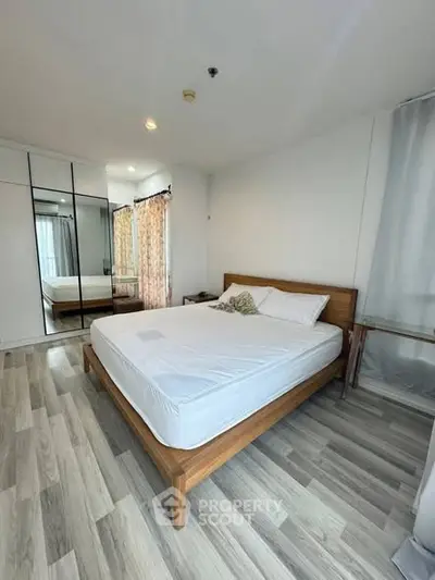 Spacious bedroom with modern wooden bed and mirrored wardrobe in a stylish apartment.
