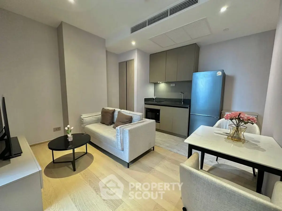 Modern open-plan living room with sleek kitchen and cozy seating area in a stylish apartment.
