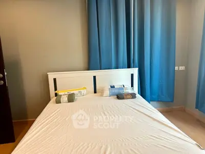 Cozy bedroom with a neatly made bed and blue curtains, perfect for relaxation and comfort.