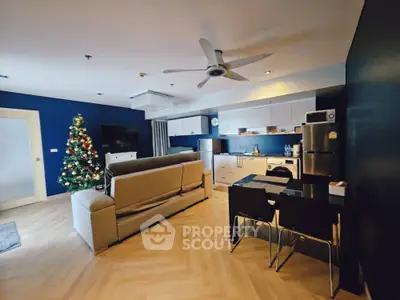Modern open-layout living room with kitchen, stylish decor, and Christmas tree
