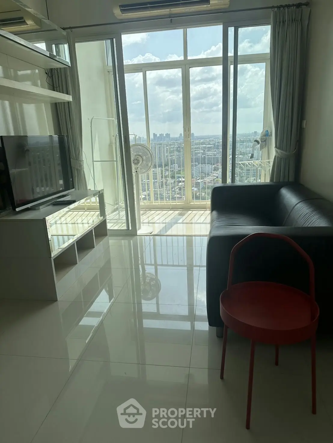 Modern living room with sleek furniture and stunning city view from large windows.