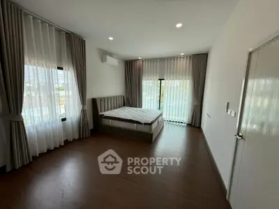 Spacious bedroom with large windows and modern decor in a luxury home.