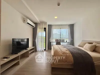 Spacious modern bedroom with large windows and natural light, featuring a cozy bed and sleek TV setup.