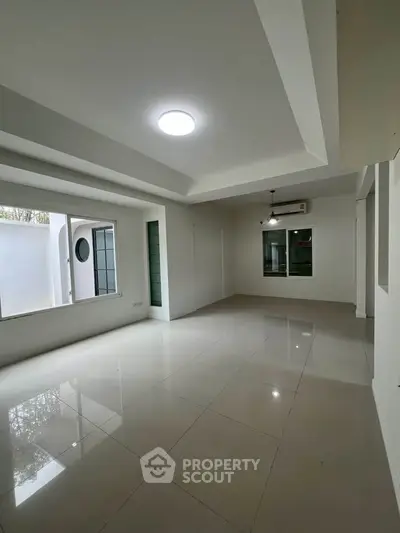 Spacious modern living room with large windows and sleek tile flooring