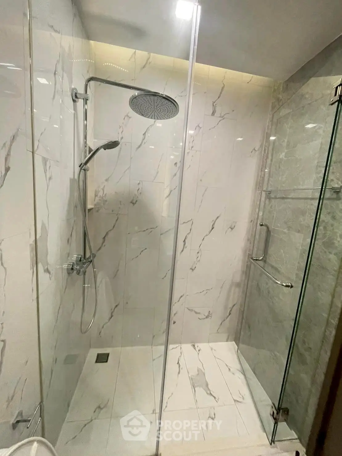 Luxurious modern bathroom with elegant marble tiles and spacious glass shower enclosure.