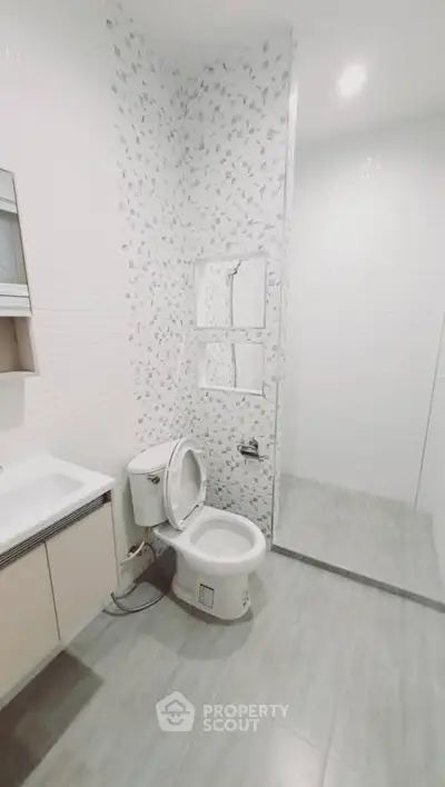 Modern bathroom with sleek design and elegant tile work, featuring a toilet and sink.