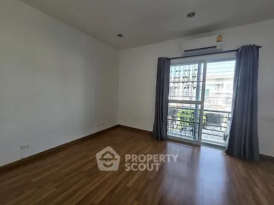 Spacious empty room with wooden flooring and large window, perfect for customization.