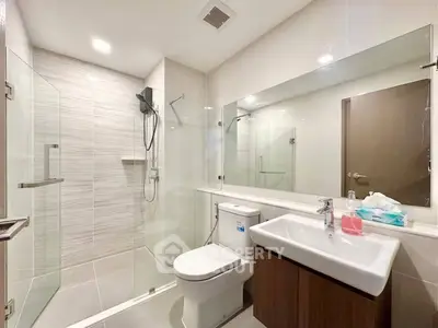 Modern bathroom with glass shower and sleek fixtures in contemporary apartment.