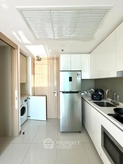 Modern kitchen with sleek appliances and washing machine in a compact layout.