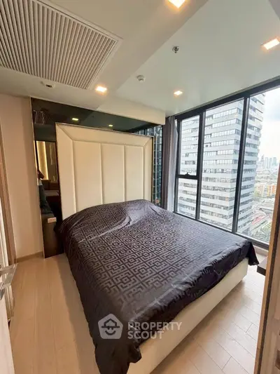 Modern bedroom with large windows and city view in high-rise apartment