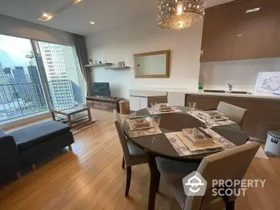 Spacious open-plan living area with modern kitchen, elegant dining set, and cozy lounge space, complemented by a city view from the balcony.