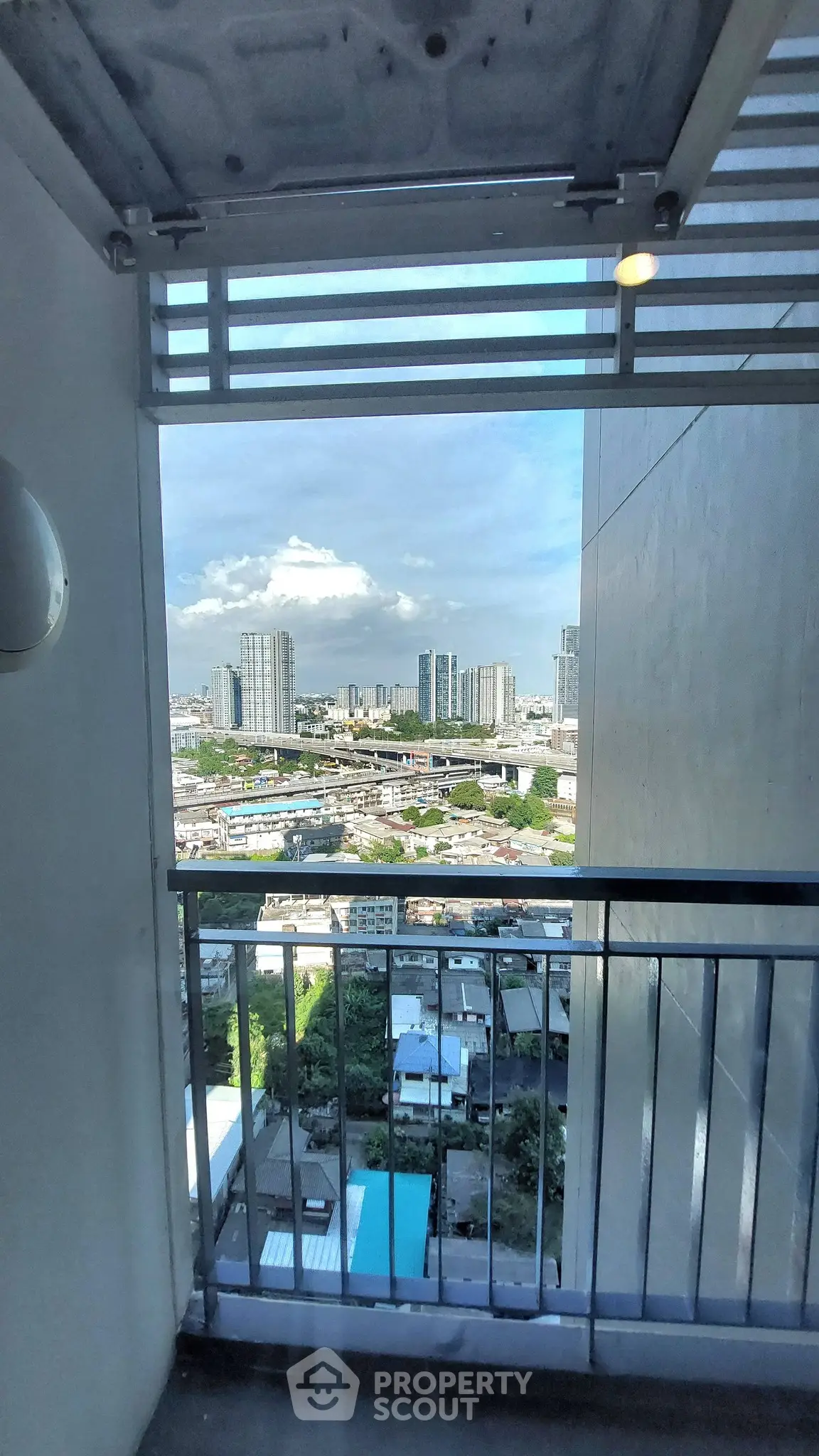 Stunning high-rise balcony view overlooking cityscape with modern skyscrapers and clear blue sky.