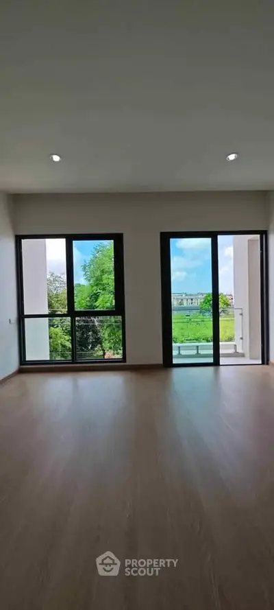 Spacious living room with large windows offering a scenic view of greenery and natural light.