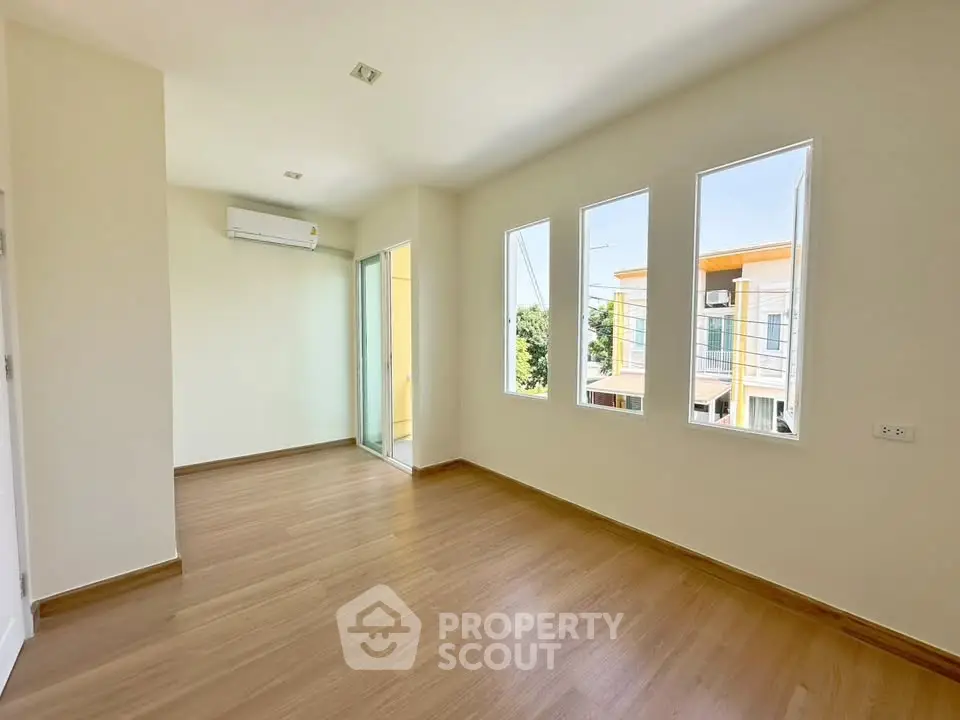 Spacious and bright room with large windows and wooden flooring, perfect for modern living.