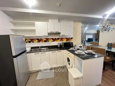 Modern kitchen with open layout, featuring washing machine and dining area in stylish apartment.