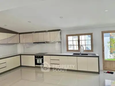 Modern kitchen with sleek cabinetry and built-in oven in a spacious open layout.