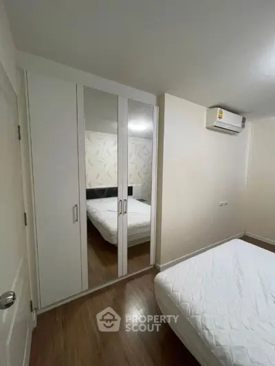 Cozy bedroom with mirrored wardrobe and air conditioning unit