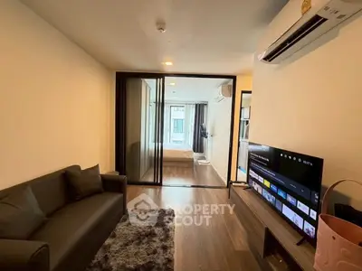 Modern living room with sleek design and open view into bedroom, featuring stylish furniture and wooden flooring.