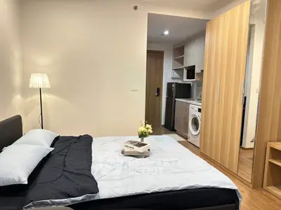Modern bedroom with cozy bed, stylish wardrobe, and compact kitchen featuring washing machine.
