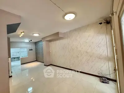 Spacious modern living room with elegant lighting and marble accent wall.
