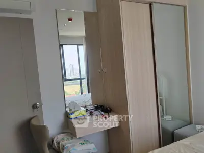 Modern bedroom with large window and built-in wardrobe in a high-rise apartment.