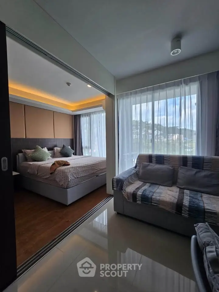 Modern bedroom with sliding doors and cozy living area, featuring large windows with scenic views.