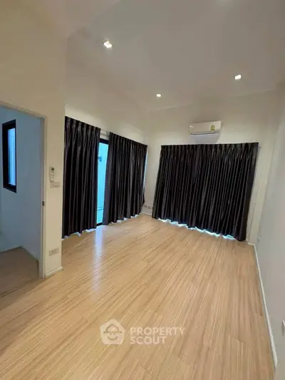 Spacious empty room with wooden flooring and large windows