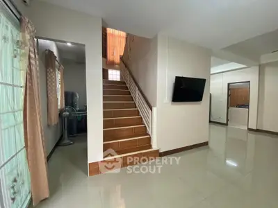Spacious modern living area with staircase and wall-mounted TV