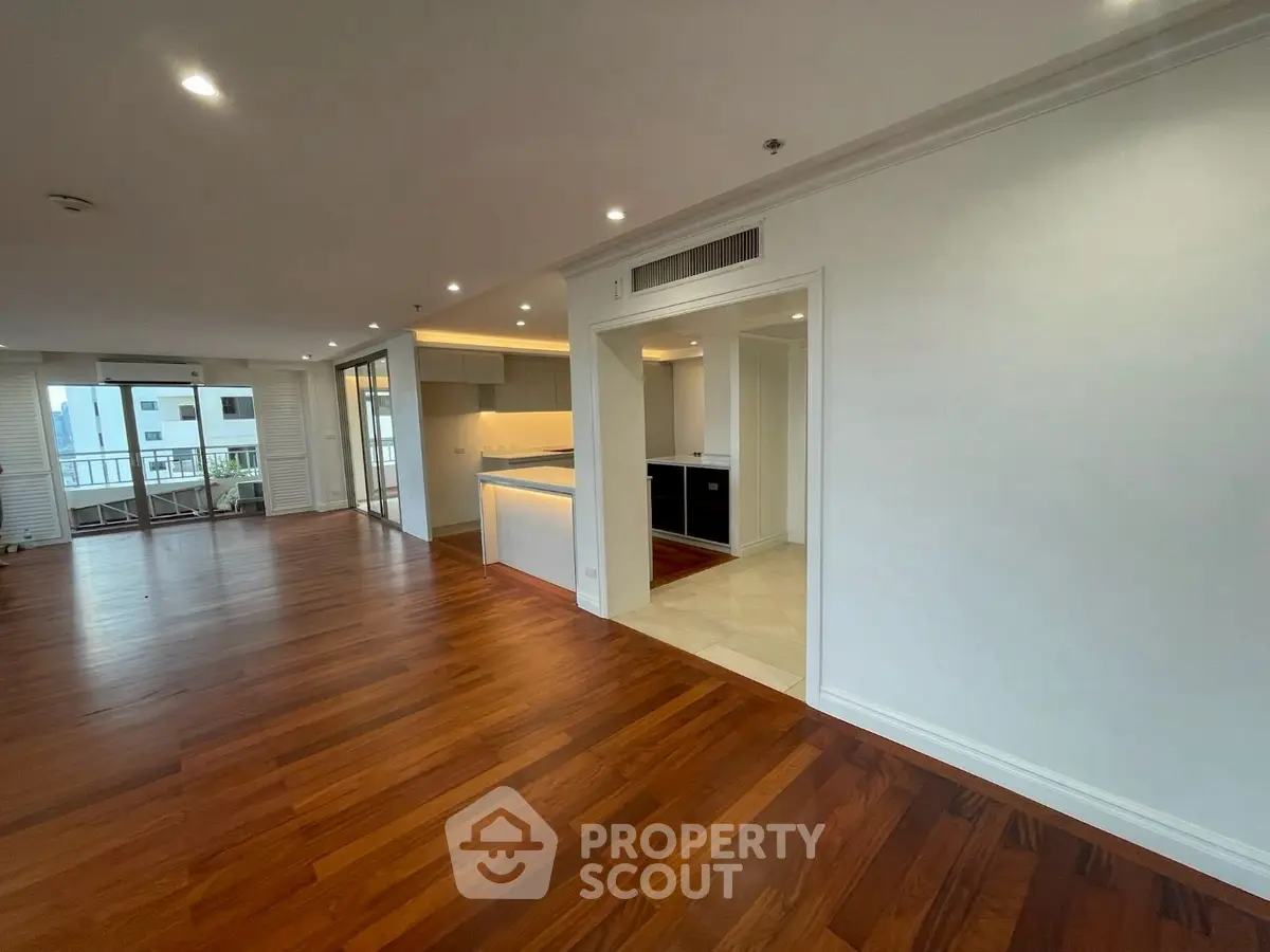 Spacious open-plan living room with hardwood floors and modern kitchen.