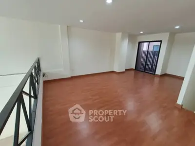 Spacious open-plan living room with wooden flooring and modern railing design.
