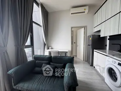Modern apartment interior with stylish living room and kitchen featuring washing machine and fridge.
