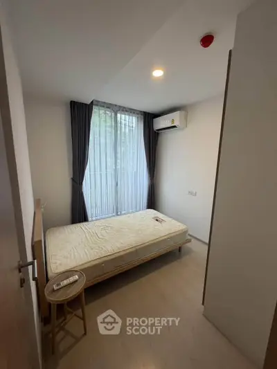 Cozy bedroom with natural light, featuring a single bed and air conditioning, ideal for comfortable living.