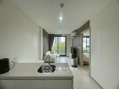 Modern open-plan living room with kitchen and city view, featuring sleek design and natural light.