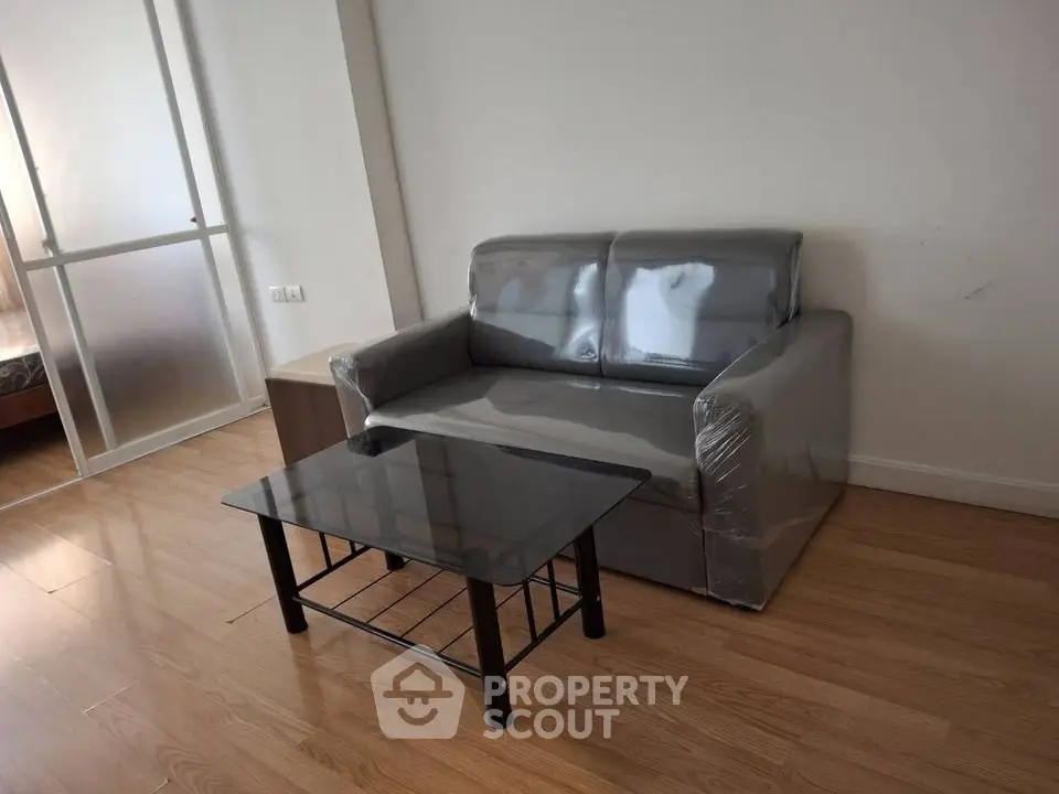 Modern living room with sleek sofa and glass coffee table on wooden flooring.