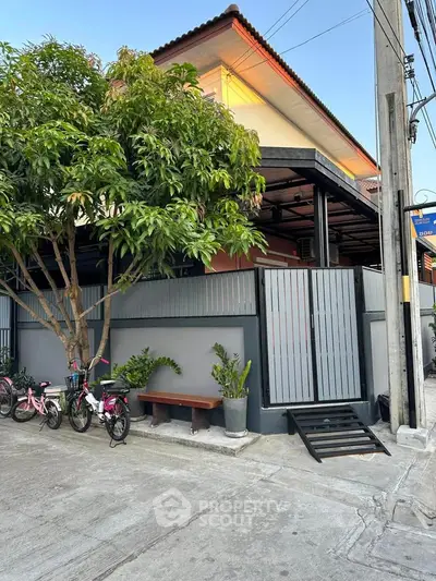 Charming two-story house with a gated entrance and lush greenery, perfect for family living.