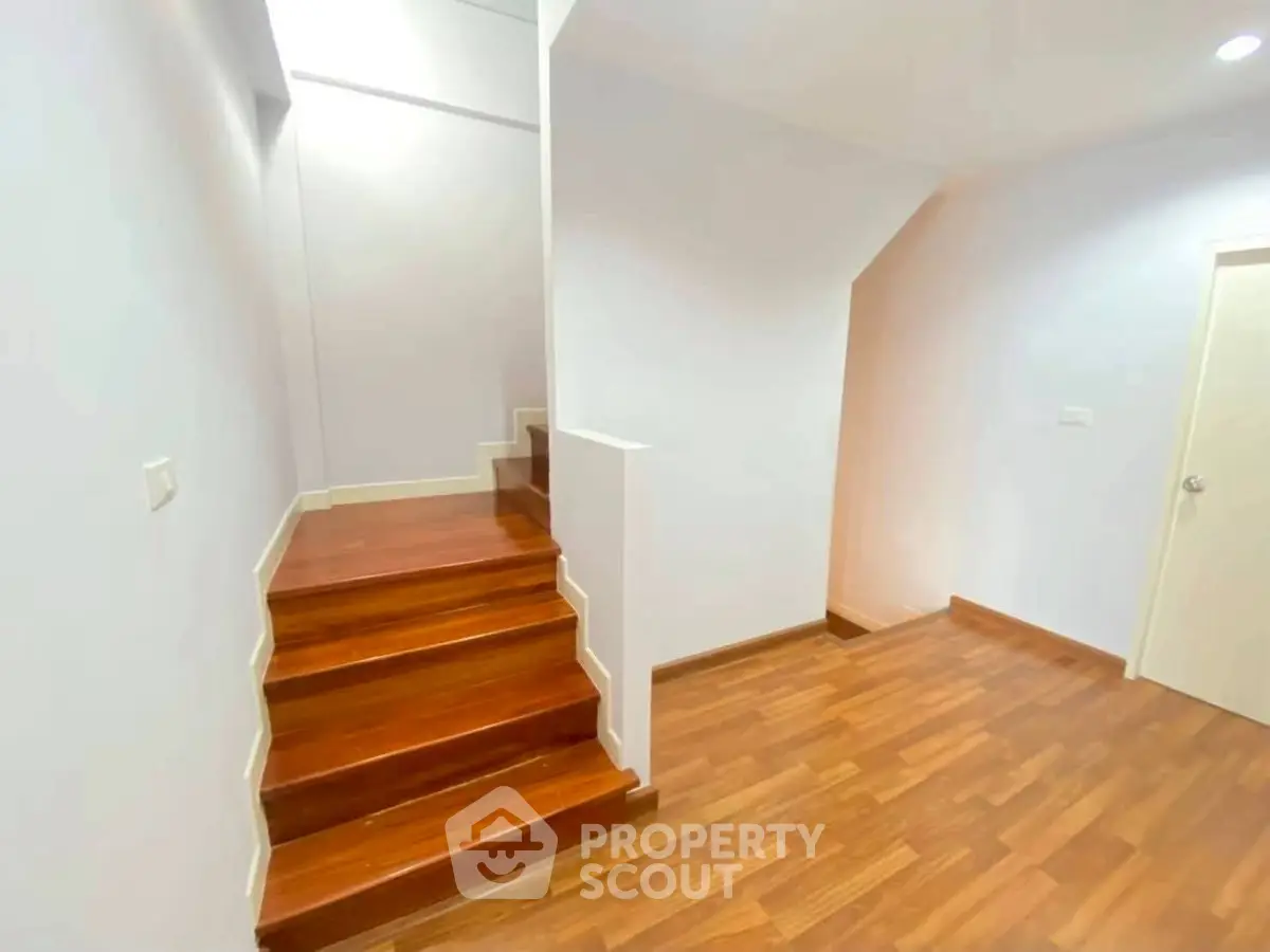 Modern interior with wooden staircase and flooring, showcasing sleek design and bright lighting.