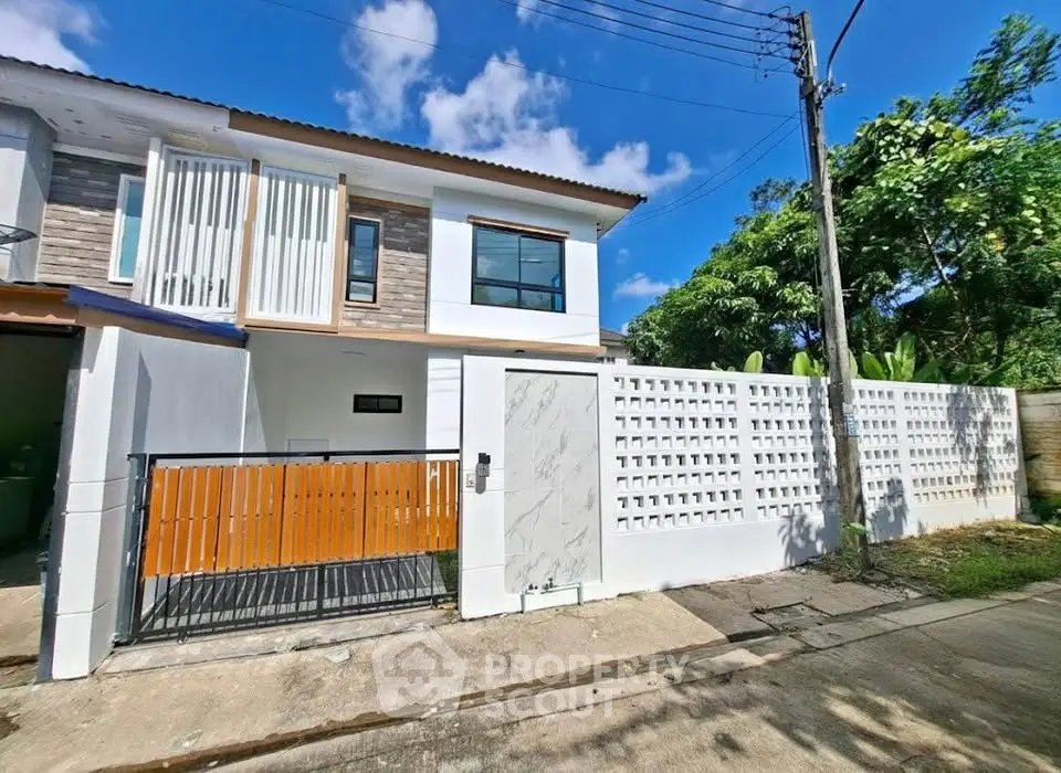 Modern two-story house with stylish facade and gated entrance in a serene neighborhood.