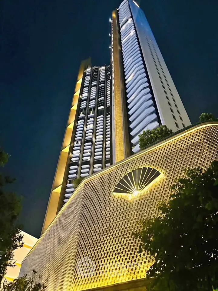 Stunning night view of a modern high-rise building with unique architectural design and illuminated facade.