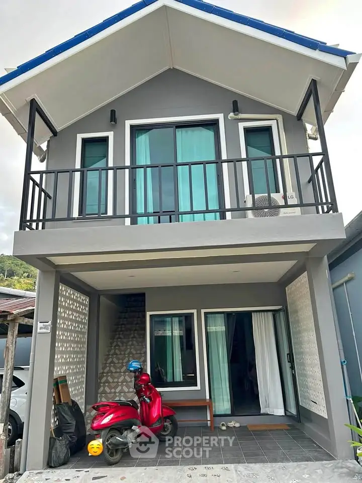 Modern two-story house with balcony and scooter parked in front, showcasing contemporary design and urban living.