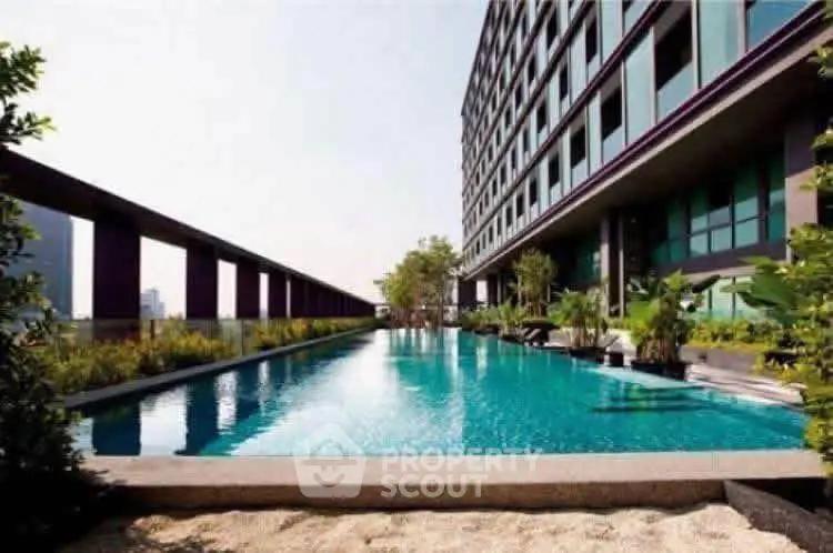 Luxurious modern apartment building with stunning rooftop pool and lush greenery.