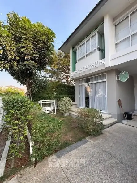 Charming two-story house with lush garden and inviting entrance