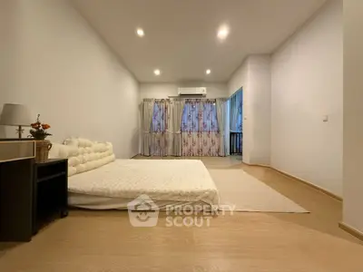 Spacious minimalist bedroom with cozy floor mattress and elegant curtains.