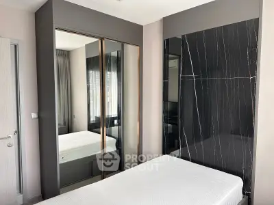 Modern bedroom with sleek mirrored wardrobe and stylish black accent wall