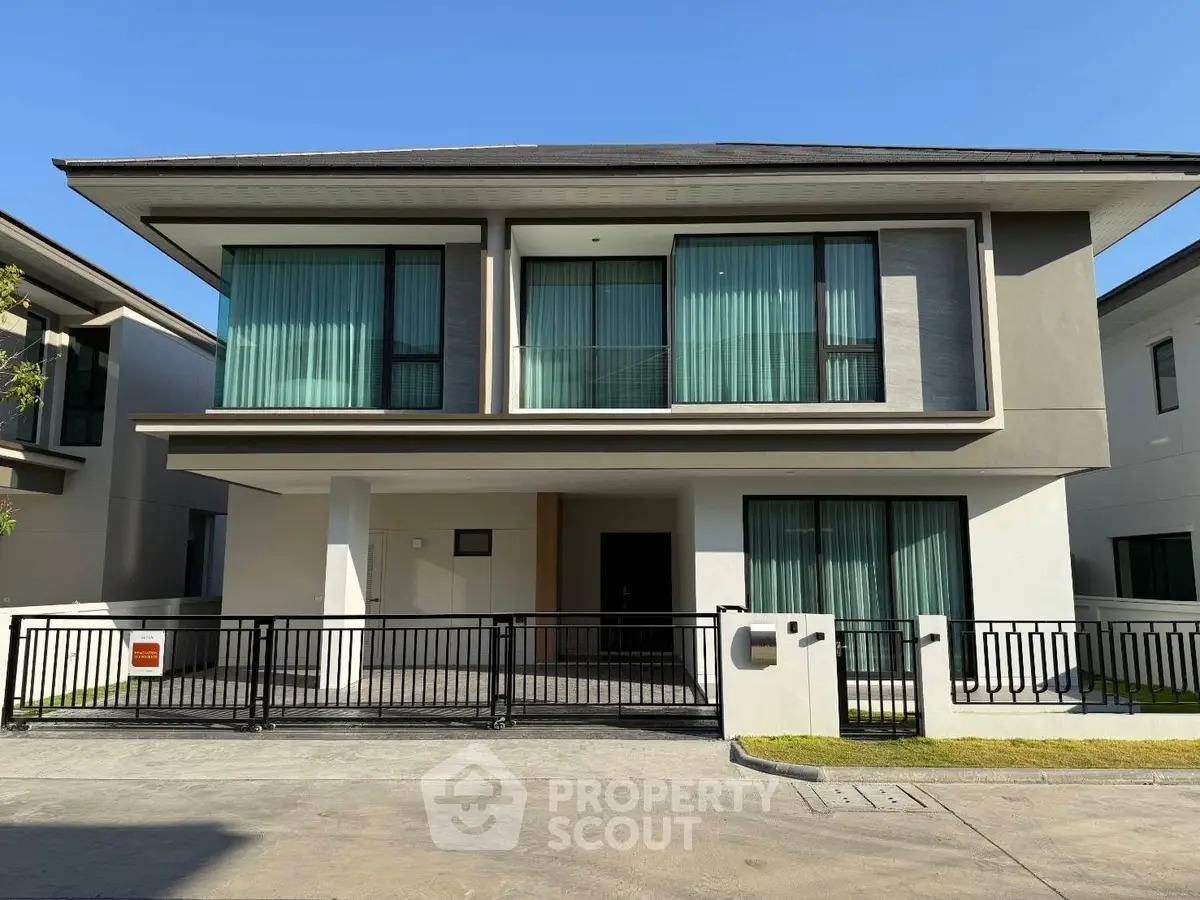 Modern two-story house with sleek design and large windows in a sunny neighborhood.