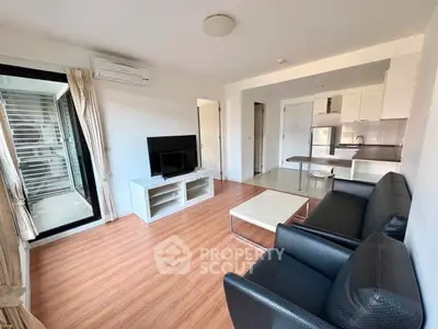 Modern living room with open kitchen, sleek furniture, and wooden flooring in a bright apartment.