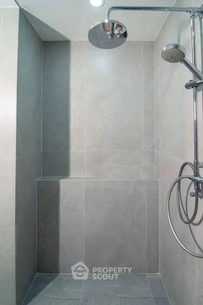 Modern bathroom shower with sleek gray tiles and rainfall showerhead.