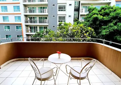 Charming balcony with seating overlooking lush greenery and modern apartment buildings.