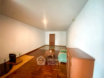 Spacious living room with wooden flooring and minimalist furniture in a modern apartment.