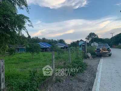Scenic rural property with lush greenery and charming houses under a picturesque sky.